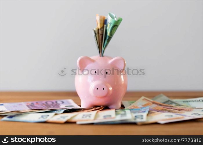 heating, energy crisis and consumption concept - close up of piggy bank with money on wooden table. close up of piggy bank with money on wooden table