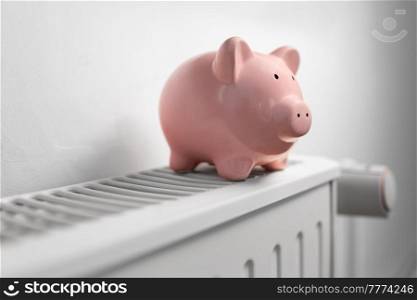 heating, energy crisis and consumption concept - piggy bank on radiator at home. piggy bank on radiator at home