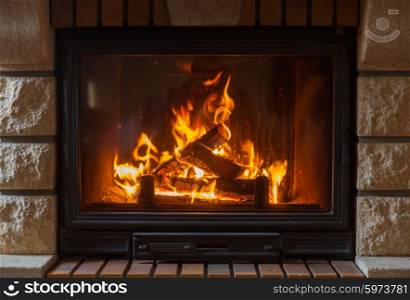 heating, warmth, fire and cosiness concept - close up of burning fireplace at home
