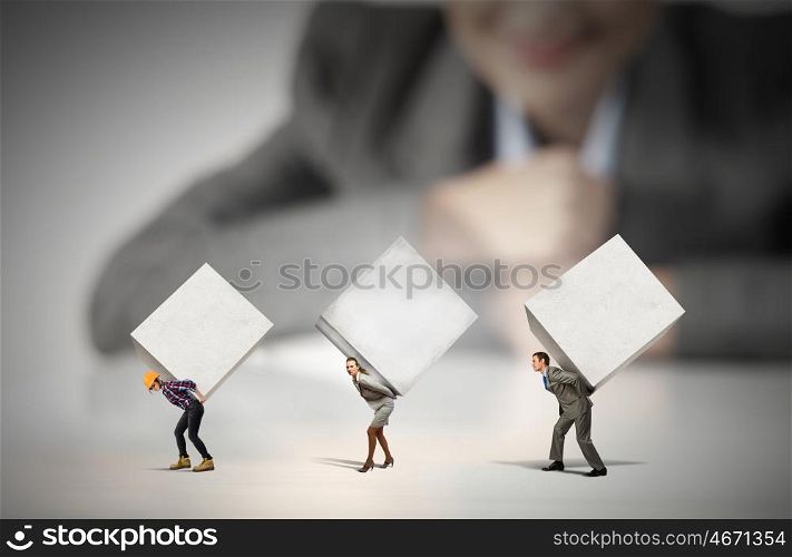 Heavy burden. Businesswoman looking at miniature of people carrying white cubes