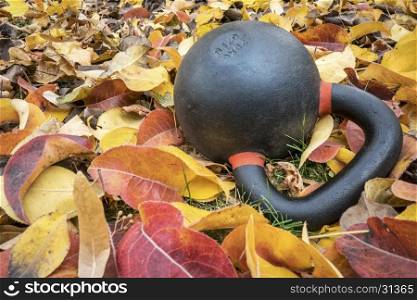 heavy exercise kettlebell in fall color leaves - outdoor fitness concept
