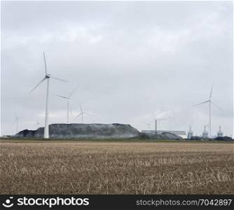 heavy industry and wind turbines behind field at Eemshaven in the north of groningen in the netherlands