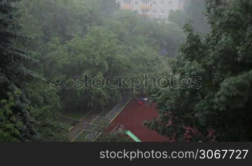 Heavy rain against the tree and a children&acute;s playground