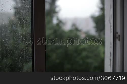 Heavy rain. Focus pulling from window to the building.
