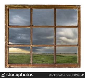 heavy storm clouds and rain over Nebraska farmland as seen through vintage, grunge, sash window with dirty glass