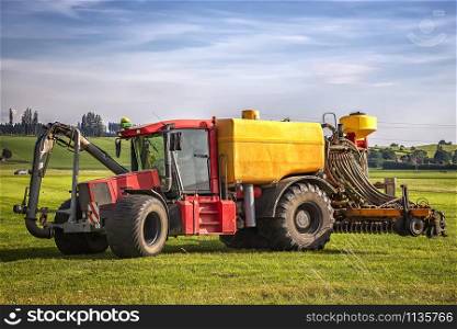 heavy tractor for application of manure on arable farmland at the field in Germany