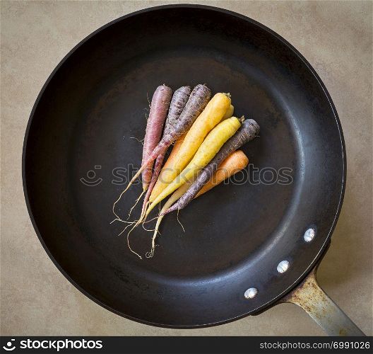 Heirloom carrots in different colours in a large black roasting pan