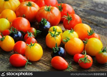 Heirloom variety tomatoes on rustic table. Colorful tomato - red,yellow , black, orange. Harvest vegetable cooking conception .. Heirloom variety tomatoes on rustic table. Colorful tomato - red,yellow , black, orange. Harvest vegetable cooking conception