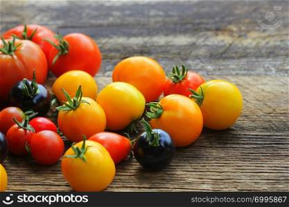 Heirloom variety tomatoes on rustic table. Colorful tomato - red,yellow , black, orange. Harvest vegetable cooking conception .. Heirloom variety tomatoes on rustic table. Colorful tomato - red,yellow , black, orange. Harvest vegetable cooking conception