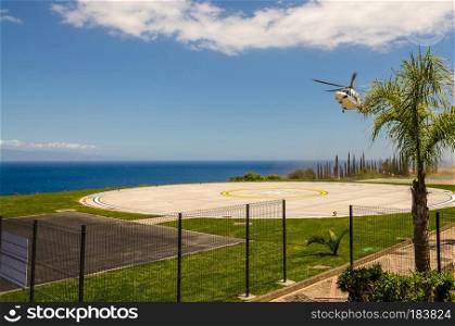 helicopter landing on a heliport with the blue sea in the background