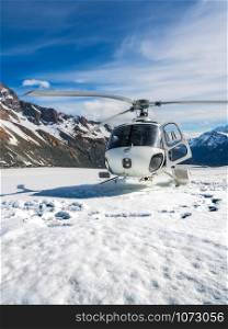 Helicopter landing on snow mountain in tasman glacier in Mt Cook, New Zealand. The helicopter service in Mt Cook offers scenic flights, glacier landing and emergency rescue.