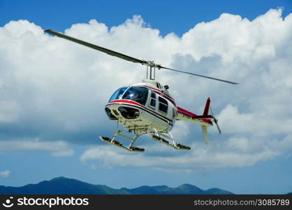 Helicopter on scenic flight with clouds and blue sky in a tropical place