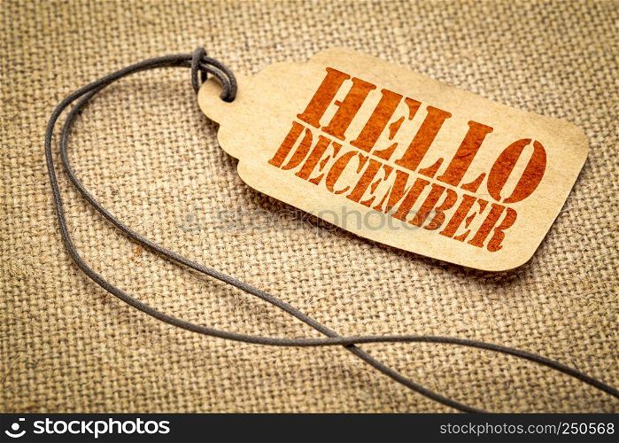 Hello December - a paper price tag with a twine against burlap canvas