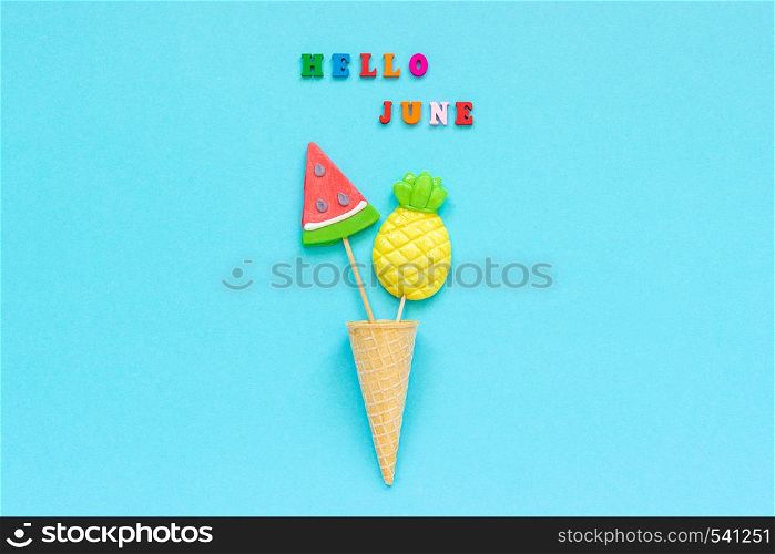 Hello June colorful text, pineapple and watermelon lollipops in ice cream waffle cone on blue paper background. Concept vacation or holidays Creative Top view Template Greeting card, postcard.. Hello June colorful text, pineapple and watermelon lollipops in ice cream waffle cone on blue paper background. Concept vacation or holidays Creative Top view Template Greeting card, postcard