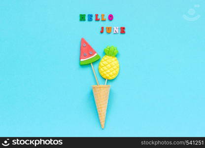 Hello June colorful text, pineapple and watermelon lollipops in ice cream waffle cone on blue paper background. Concept vacation or holidays Creative Top view Template Greeting card, postcard.. Hello June colorful text, pineapple and watermelon lollipops in ice cream waffle cone on blue paper background. Concept vacation or holidays Creative Top view Template Greeting card, postcard