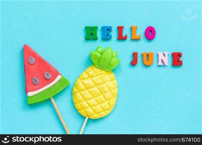 Hello June colorful text, pineapple and watermelon lollipops on stick on blue paper background. Concept vacation or holidays Creative Top view Template Greeting card, postcard.. Hello June colorful text, pineapple and watermelon lollipops on stick on blue paper background. Concept vacation or holidays Creative Top view Template Greeting card, postcard