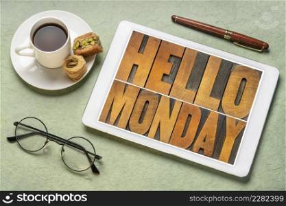 Hello Monday cheerful banner - letterpress wood type text on a digital tablet with a cup of coffee, starting a new working week concept