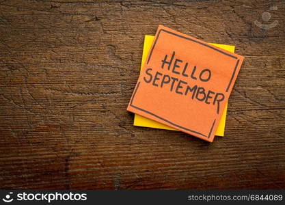 Hello September welcome note. Hello September - handwriting on a sticky note against rustic wood