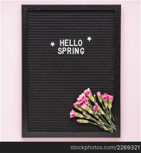 hello spring inscription with pink flowers black board