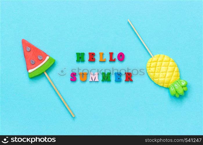 Hello summer colorful text, pineapple and watermelon lollipops on stick on blue paper background. Concept vacation or holidays Creative Top view Template Greeting card, postcard.. Hello summer colorful text, pineapple and watermelon lollipops on stick on blue paper background. Concept vacation or holidays Creative Top view Template Greeting card, postcard