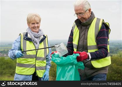 Helpful Senior Couple Collecting Litter In Countryside