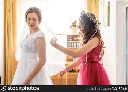 helping the bride to put her wedding dress on