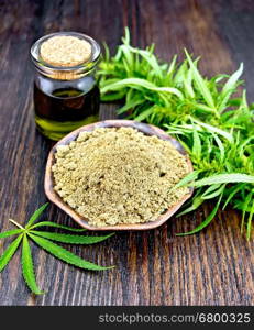 Hemp flour in a clay bowl in a glass jar oil, cannabis leaf on a background of wooden boards