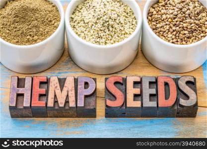 hemp products: seeds, hearts (shelled seeds) and protein powder in small ceramic bowls on a grunge wood with atext in vintage letterpress wood type