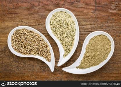 hemp seeds, hearts and protein powder in teardrop shaped bowls against grunge wood