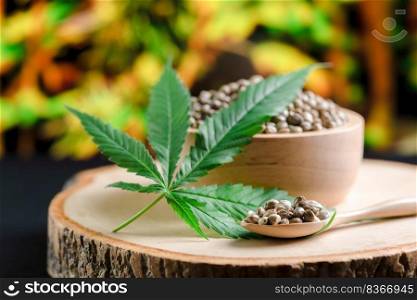 Hemp seeds on round wooden bowl with hemp leaf. Legalized cannabis concept for medical and healthcare purpose.. Legalized cannabis concept for medical and healthcare purpose shown by hemp seed