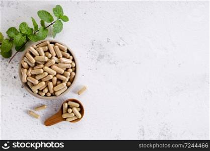herb capsules, nutritional supplement, in a small bowl on marble background. alternative healthy lifestyle concept.