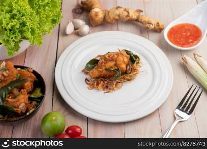 Herb fried chicken on a white plate and dipping sauce with lemongrass, garlic, lemon and tomatoes on a wooden floor