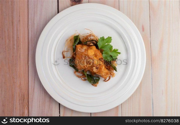 Herb fried chicken on a white plate on a wooden floor.