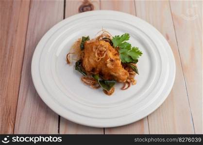 Herb fried chicken on a white plate on a wooden floor.