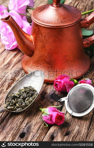 herb rose buds tea. Stylish copper kettle, tea rose buds and dry tea leaf