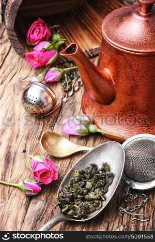 herb tea made from tea rose petals. Stylish copper kettle, tea rose buds and dry tea leaf
