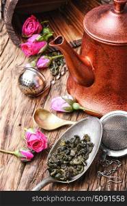 herb tea made from tea rose petals. Stylish copper kettle, tea rose buds and dry tea leaf