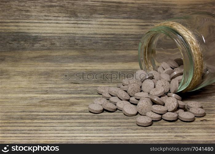 Herbal brown pills on wooden background.