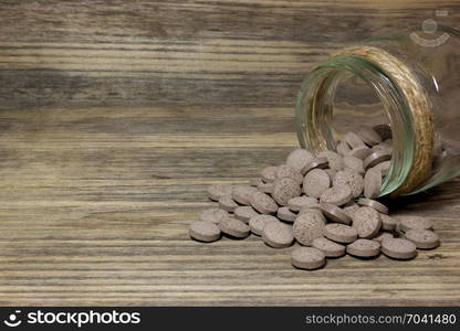 Herbal brown pills on wooden background.