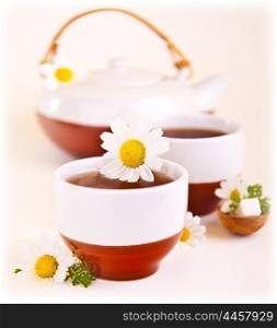 Herbal chamomile cup of tea with daisy flower, shallow depth of field, healthy drink, relaxing anti stress spa beverage, teatime