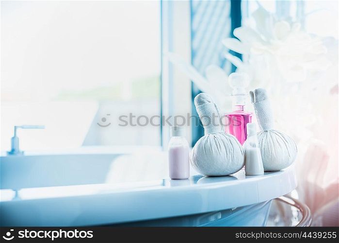 Herbal compress stamps , pink lotion bottle on light luxury bath at window. Spa or wellness background