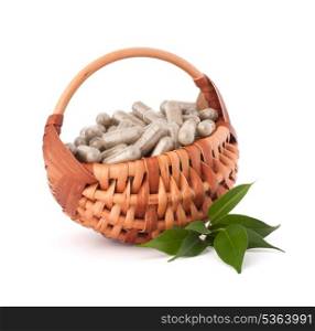 Herbal drug capsules in wicker basket isolated on white background cutout. Alternative medicine concept.