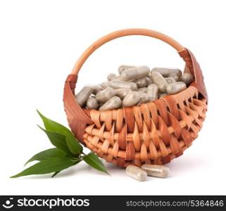 Herbal drug capsules in wicker basket isolated on white background cutout. Alternative medicine concept.