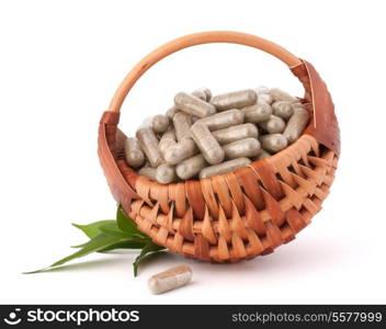 Herbal drug capsules in wicker basket isolated on white background cutout. Alternative medicine concept.