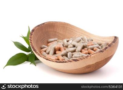 Herbal drug capsules in wooden plate isolated on white background cutout. Alternative medicine concept.