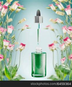 Herbal facial serum bottle with pipette and flowers plats on blue background, front view