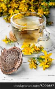 Herbal Hypericum tea.. Cup with herbal tea from the petals Hypericum on wooden background