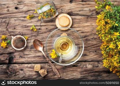 Herbal Hypericum tea.. Hypericum.Glass cup with herbal tea from inflorescences Hypericum on a wooden background