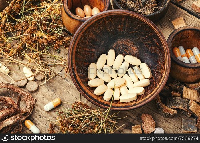 Herbal medical pills with healing plant on wooden table. Medical pills with healing herbs
