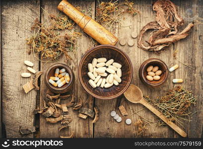 Herbal medical pills with healing plant on wooden table. Medicine herbal pills